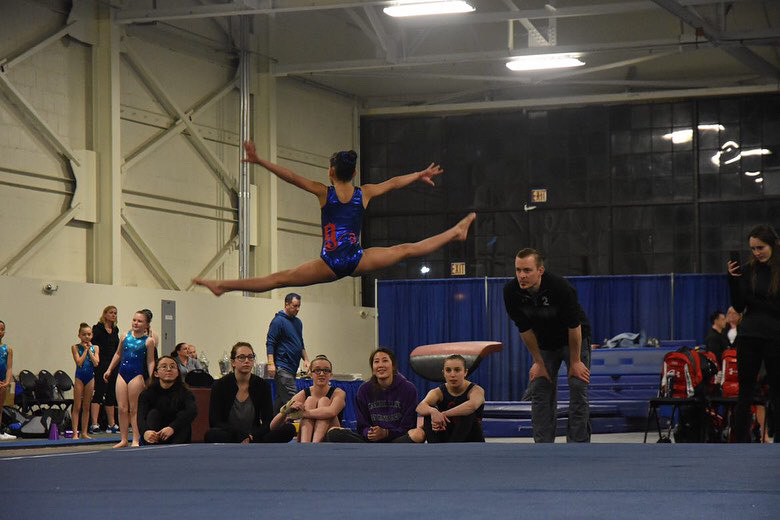 Ava Enriquez leaping through the air at a Gymnastics compeition
